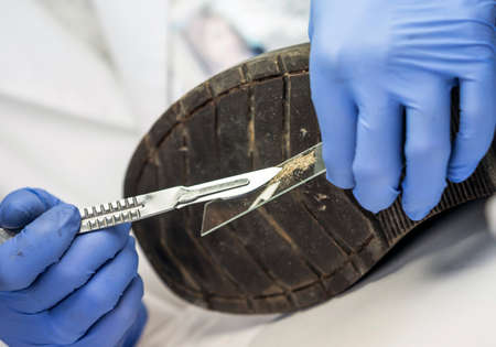 Specializing police officer analyzes ground in a victim's shoe murder with one tweezers, conceptual...