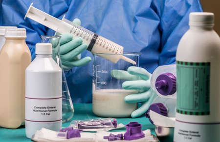 Nurse extracts enteral nutrition content with syringe, pailative care in a hospital, conceptual...