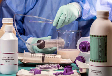 Nurse extracts enteral nutrition content with syringe, pailative care in a hospital, conceptual imageの写真素材