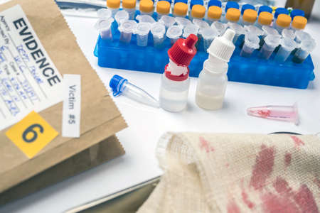 Specialist cop examines piece of blood-stained cloth belonging to murder victim, concept image