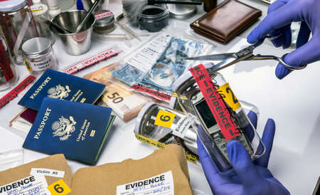 Scientific police opens with scissors a bag of evidence of a crime in scientific laboratoryの写真素材