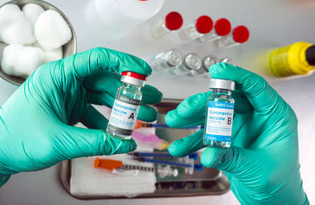 Nurse holds two covid-19 vaccines from different laboratories, conceptual image