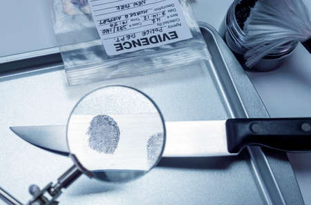 research with a magnifying glass footprint on a knife, conceptual imageの写真素材