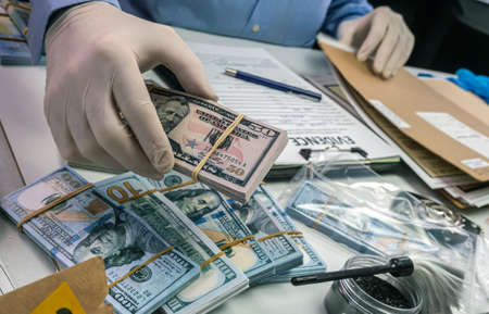 Specialised police officer notes dollar banknote reference of a robbery, conceptual image