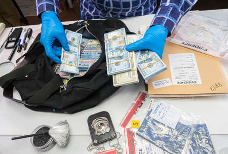 Specialised police officer Counting dollar banknotes in crime lab, conceptual imageの写真素材