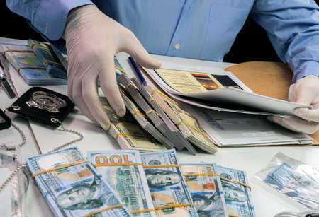 Specialised police officer notes dollar banknote reference of a robbery in criminal investigation unit, conceptual imageの写真素材