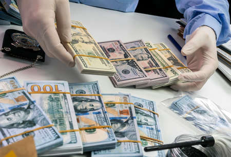 Specialised police officer Counting dollar banknotes in crime lab, conceptual imageの写真素材