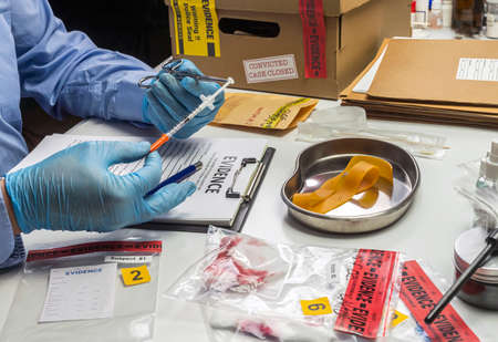 Specialized police analyzes syringe with traces of blood from a victim overdose with tweezers,...