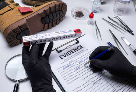 Police scientist investigates a shoe sole tape tread involved in crime lab murder, concept imageの写真素材