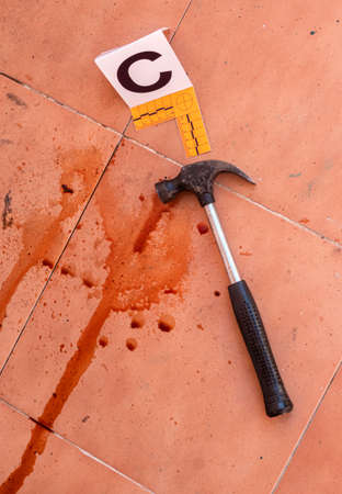 Bloody hammer on the ground marked with number, crime scene, conceptual image