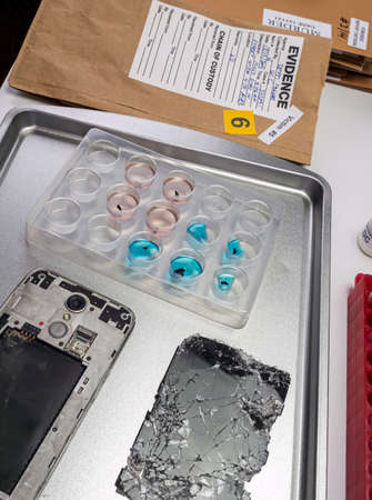 Scientific police extract pieces of burnt smartphone involved in lab murder, concept image