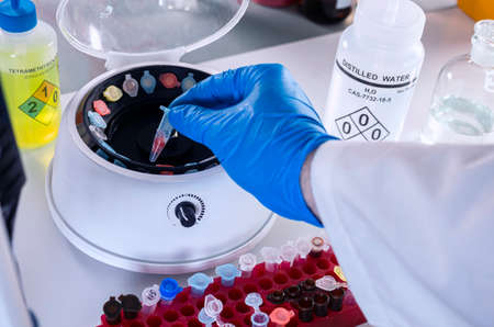 Police scientist inserts vial into microcentrifuge in crime lab,の写真素材