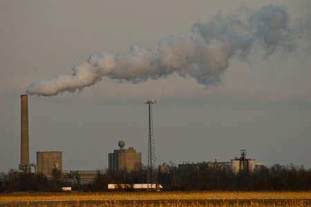Field and factory behind it with smoke stackの写真素材