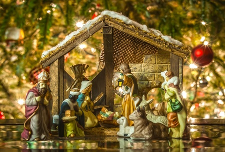 Old handmade nativity scene in front of a christmas treeの写真素材