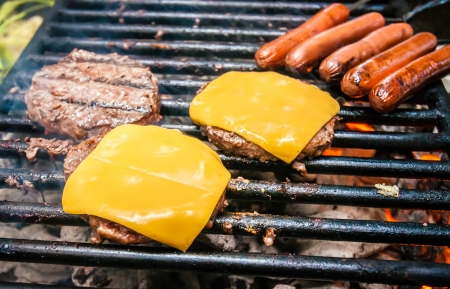 hamburgers with cheese and hot dogs on grille on camping tripの写真素材