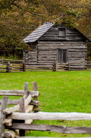 Beautiful Autumn scene showing rustic old log cabin surrounded by split rail fenceの写真素材