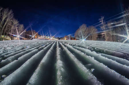 snow groomed trail at a ski resort at nightの写真素材