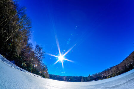 ice and snow frozen over lake on sunny day