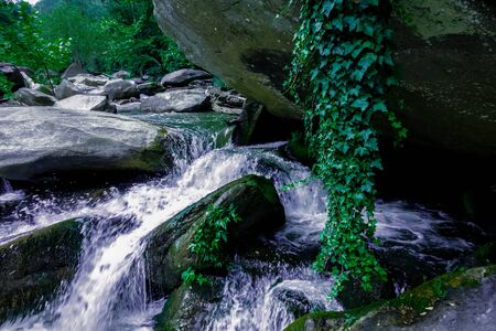 river stream flowing over rock formations in the mountainsの写真素材