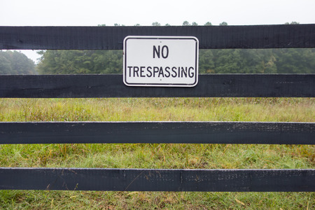 No trespassing sign against backdrop of farmlandの写真素材