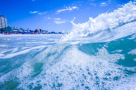 blue crystal water waves crashing on beachの写真素材