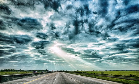 freeway through country landscape with dramatic skyes and sun raysの写真素材