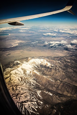 Flying over rocky mountains in spring at day timeの写真素材