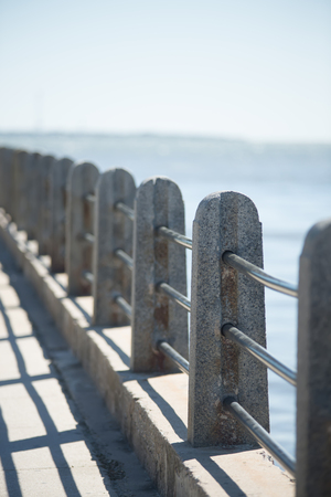 guear rail and security fence along harbor pier in portの写真素材