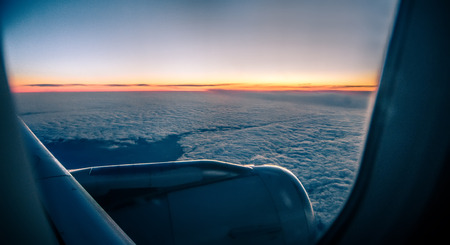 Clouds and sky as seen through window of an aircraft at sunrise