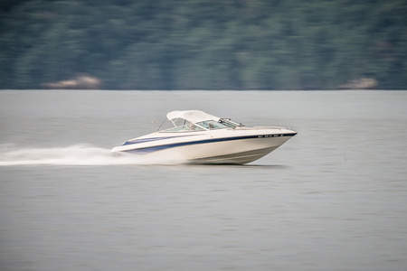 abstract blur of nature and fast moving boat on lake