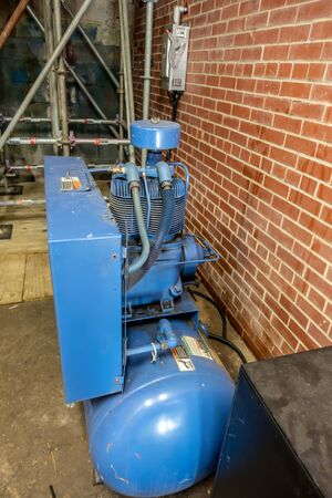 industrial grade air compressor next to masonry brick wallの写真素材