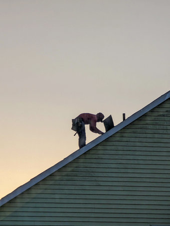 Contractor in Silhouette working on a Roof Topの写真素材