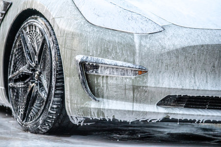 Manual car wash. Washing luxury vehicle with white foamy detergent. Automobile cleaning self serviceの写真素材