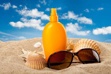 Suntan oil and dark glasses on the beachの写真素材