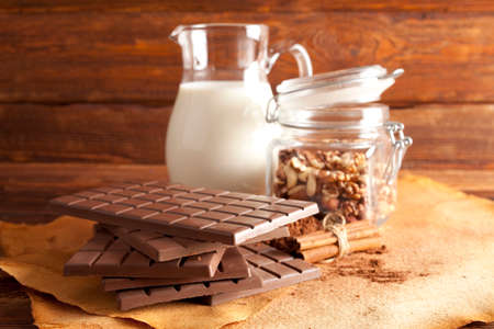 Chocolate, jug of milk, cinnamon, cocoa and mixed nuts in a jarの写真素材
