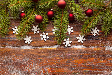 Branch of Christmas tree, red baubles and snowflakes on wooden backgroundの写真素材