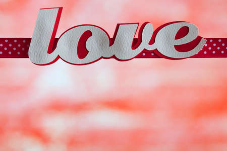 Inscription love and a red ribbon on a red backgroundの写真素材