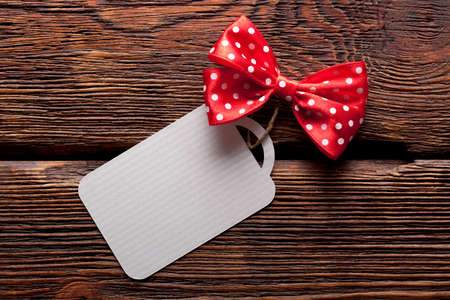 Blank label and red bow on wooden backgroundの写真素材