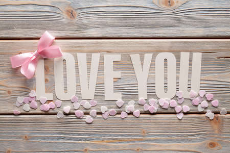 Love You - Inscription and a pink bow on wooden backgroundの写真素材