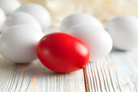One red and many white eggs on wooden backgroundの写真素材
