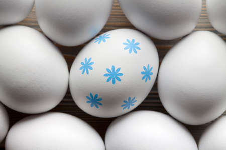 One egg with blue pattern and many white eggsの写真素材