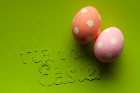 Two Easter eggs and inscription on green paper background