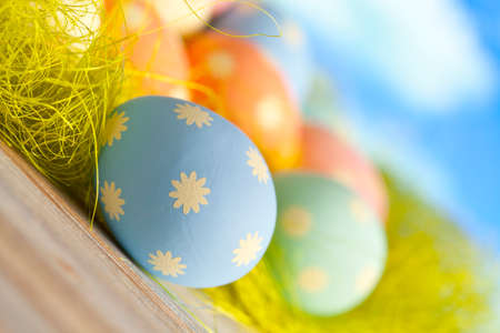 Painted Easter eggs in pastel colors on green and blue background