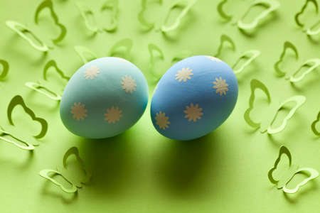 Two Easter eggs and many paper butterflies on green background