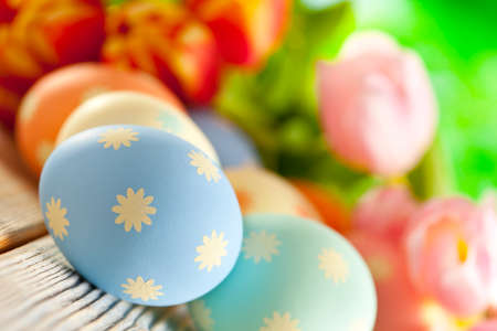 Painted Easter eggs in pastel colors and colorful spring flowersの写真素材