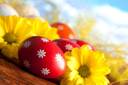 Red Easter eggs and yellow flowers on nature backgroundの写真素材