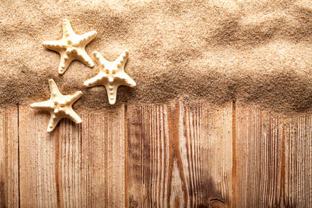 Three starfishes on sand and wooden planksの写真素材