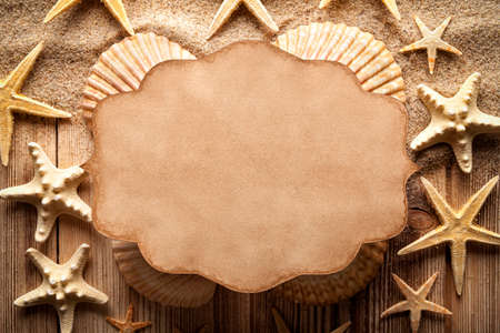 Blank paper card and shells on sand and wooden tableの写真素材