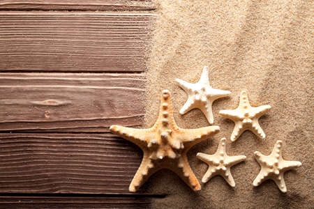 Starfishes on sand and wooden tableの写真素材