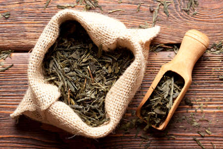 Dried tea leaves in jute bag on wooden planksの写真素材